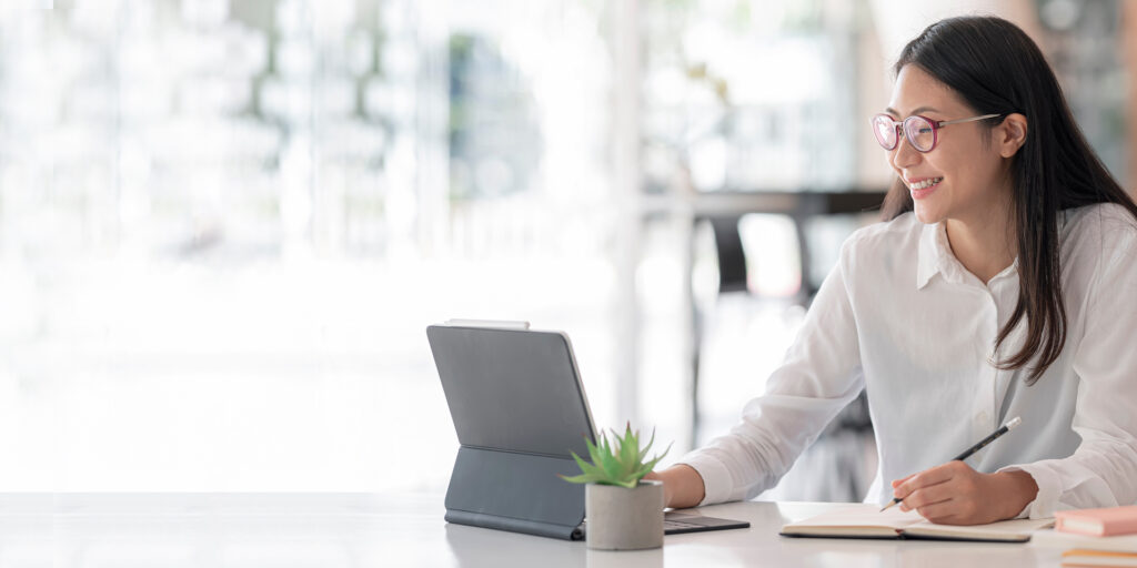 Young woman smiling while working with tablet at office, success