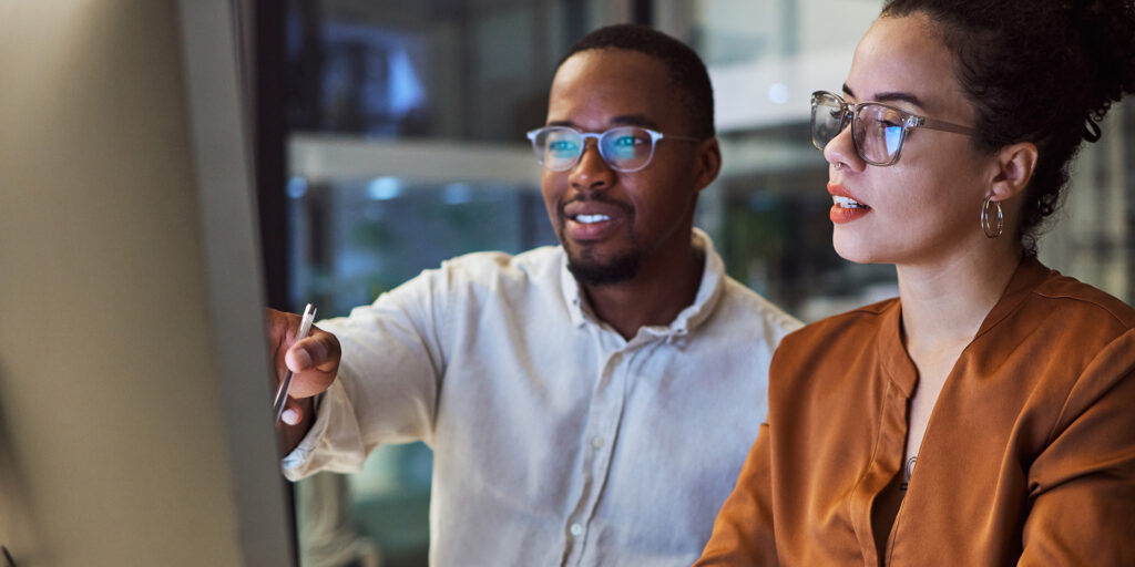 Night training, teamwork and employees planning marketing strategy in a dark office on computer at work. Corporate African man and woman talking about business collaboration during overtime together