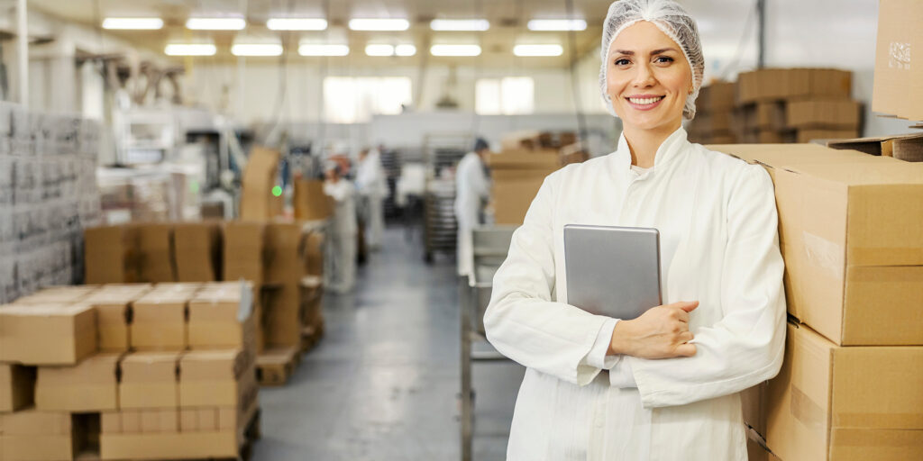 A food factory supervisor is leaning on boxes with goods while h