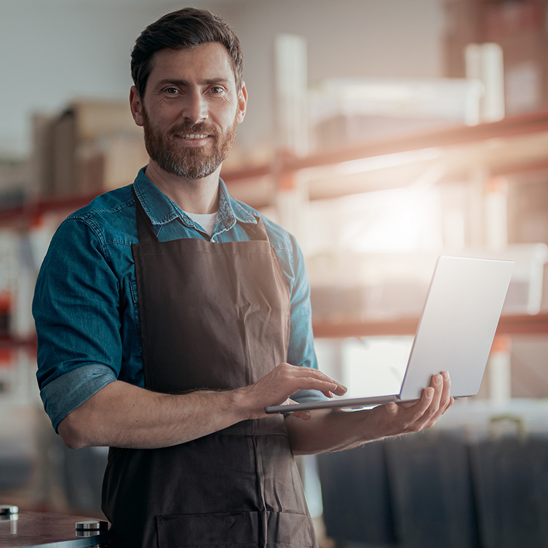 Male worker working laptop on background of warehouse