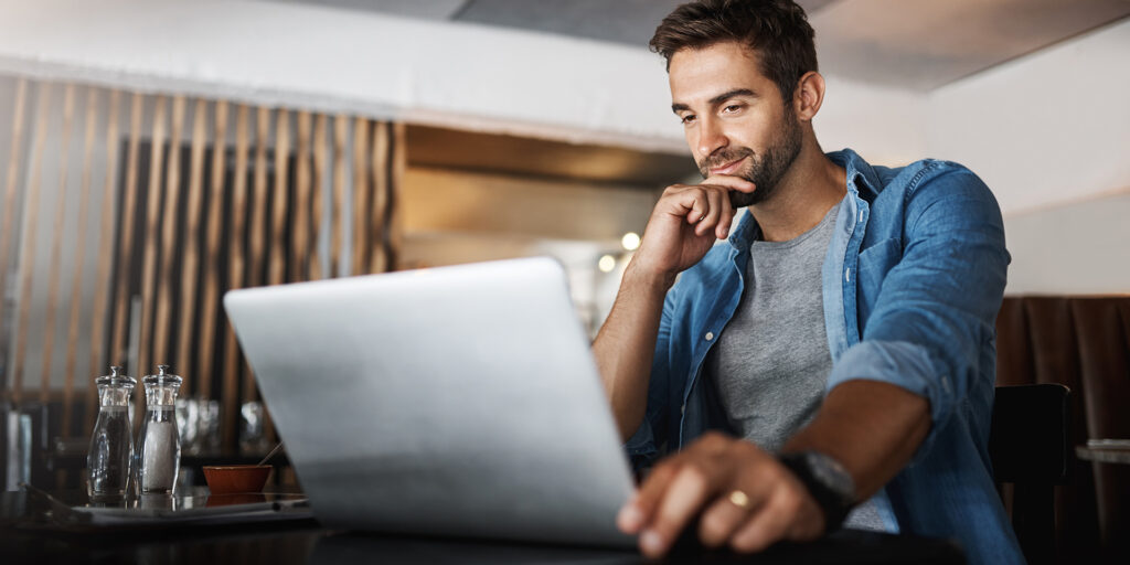 Laptop, research and male freelancer in a coffee shop reading for a freelance project. Remote work, technology and man thinking, browsing and working online with a computer at a cafe or restaurant.